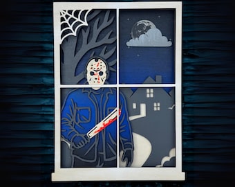 May include: A multi-layered wooden art piece depicting a scene through a window. The artwork features a figure in a hockey mask holding a bloody machete, a spider web, a tree, a full moon, and a house. The color palette includes blue, gray, white, and red.