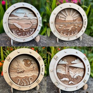 Puede incluir: Cuatro cajas de sombra de madera con temática náutica. Cada marco redondo presenta un diseño en capas que representa escenas oceánicas: una ballena, una puesta de sol con una tortuga, un barco con tentáculos y un faro. Los marcos son de color claro con detalles interiores marrones oscuros.