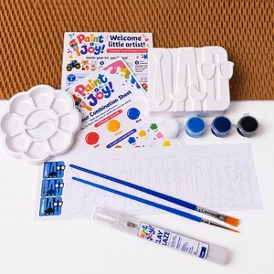 May include: A craft kit featuring a white ceramic DAD sign with tie, moustache, and glasses icons, a white flower-shaped paint palette, two blue-handled paintbrushes, a tube of clay glaze, four small paint pots, and instructional sheets.