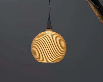May include: A spherical pendant light fixture with a spiral design. The light is a warm yellow color, and the fixture is suspended from a dark cord. The background is a dark gray.