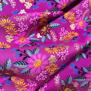 Könnte beinhalten: Pinkfarbener Stoff mit einem floralen Muster mit goldenen, gelben und rosa Blüten. Der Stoff hat einen dezenten Glanz und eine weiche Textur.