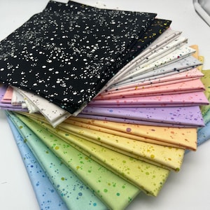 Könnte beinhalten: Ein Stapel von 15 Stoffquadraten mit einem gesprenkelten Muster in verschiedenen Pastellfarben, darunter Schwarz, Weiß, Rosa, Lila, Orange, Gelb, Grün und Blau. Der Stoff hat einen dezenten Schimmer.