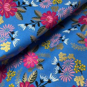 Könnte beinhalten: Blauer Stoff mit floralem Muster. Das Design zeigt große rosa Blüten mit goldenen Akzenten, kleinere rosa und gelbe Blüten und weiße Blüten. Die Blätter sind grün und gold.