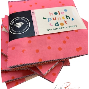 Könnte beinhalten: Ein Stapel rosa Stoffquadrate mit orangefarbenen Punkten. Die Quadrate sind mit "hole punch dot" von Kimberly Kight beschriftet. Das Paket ist ein "Charm Pack" mit 42 Teilen, jeweils 12,7 cm groß. Das Ruby Star Society-Logo ist ebenfalls sichtbar.