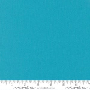 Könnte beinhalten: Ein fester türkisfarbener Stoffmuster mit einem Lineal und dem aufgedruckten Text "moda". Die Website-Adresse "www.modafabrics.com" ist ebenfalls auf dem Muster aufgedruckt.