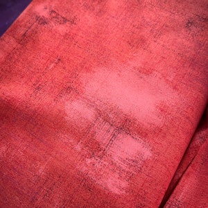 May include: Red fabric with a textured, distressed look. The fabric has a subtle sheen and a slightly rough feel.