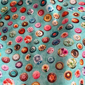 Könnte beinhalten: Ein türkisfarbener Stoff mit einem sich wiederholenden Muster aus bunten Knöpfen. Die Knöpfe sind in verschiedenen Formen und Größen, einige mit Blumendesigns.