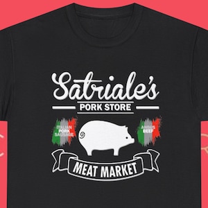 May include: Black t-shirt with a white graphic featuring the text "Sabriale's Pork Store" above a pig illustration and "Meat Market" below. Includes Italian and Angus beef flags.