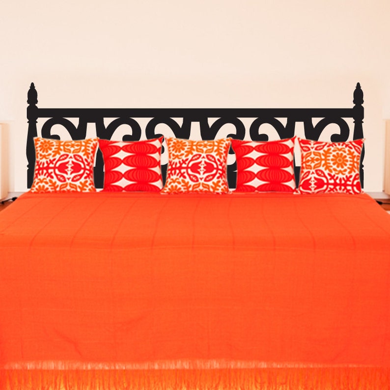Puede incluir: Un adhesivo de cabecero negro con un dise&ntilde;o ornamentado, aplicado a una cama con un edred&oacute;n naranja y cinco almohadas de dise&ntilde;o. Las almohadas son blancas con dise&ntilde;os geom&eacute;tricos naranja y rojo.