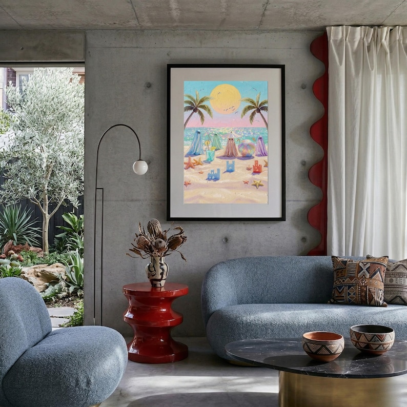 Tiny Ghosts Beach Day Wall Art shown as a large framed print on a modern concrete wall in an industrial living room with a blue curved sofa. The vibrant colors and quirky ghost theme act as a bold centerpiece, blending sophisticated architecture with whimsical coastal artistry. This mockup highlights how the print anchors a contemporary space with its unique story and impasto depth... — bring calm artistry to your walls.