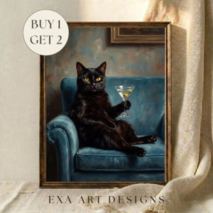 Op de afbeelding: Een ingelijste kunstdruk met een zwarte kat met gele ogen die op een blauwe fauteuil zit en een martiniglas met een olijf vasthoudt. De tekst BUY 1 GET 2 is linksboven zichtbaar en EXA ART DESIGNS staat onderaan.