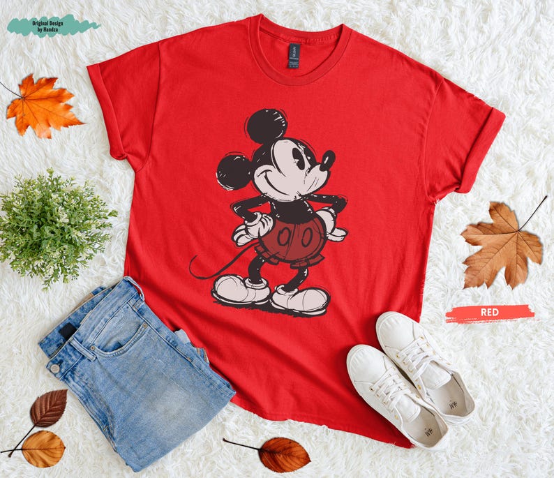 Puede incluir: Una camiseta roja con un dibujo de Mickey Mouse, combinada con vaqueros azules y zapatillas blancas. La palabra "RED" est&aacute; escrita en un rect&aacute;ngulo rojo. Ropa.
