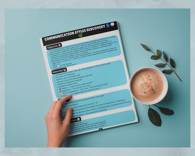 May include: A printed document titled Communication Styles Discovery with sections for Objective, Materials, and Instructions. The page features light blue text boxes, black headers, and small icons. A white ceramic mug with a brown beverage sits nearby.