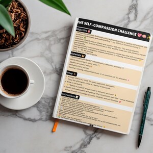 May include: A white notebook titled The Self-Compassion Challenge with black text and peach-coloured sections. The page outlines objectives, materials, setup, and instructions for a group activity. A black pen rests beside the notebook.