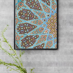 Puede incluir: Obra de arte enmarcada con un intrincado patrón geométrico en tonos azules, marrones, rojos y dorados. El diseño presenta formas complejas en forma de estrella y elementos de mosaico, creando una composición visualmente rica. La obra está enmarcada en negro.