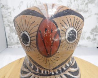 May include: A hand-painted owl figurine with a tan body, black and white accents, and a red beak. The owl's eyes are large and round, with black pupils and white irises. The figurine is a decorative item.