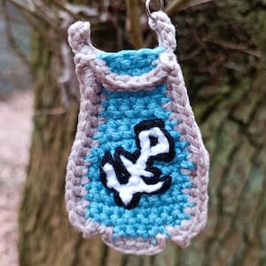 Può includere: Portachiavi all'uncinetto fatto a mano con design a mantello blu e grigio. Il mantello presenta un'ancora bianca e nera. Il portachiavi è sospeso a un anello color argento, perfetto per chiavi o borse.