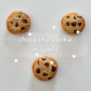 Op de afbeelding: Drie ronde magneten in de vorm van chocolate chip cookies, lichtbruin met donkere chocoladeschilfers. De tekst "choco chip cookie magnets" staat in het midden van de afbeelding.