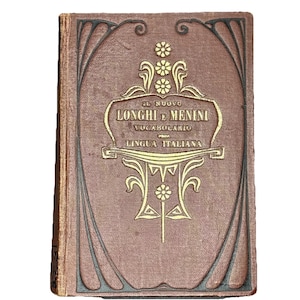 May include: A vintage Italian dictionary, "Il Nuovo Longhi e Menini Vocabolario Lingua Italiana," with a brown cover and gold lettering. The cover features an ornate design with floral and geometric elements. The book is closed and slightly worn.