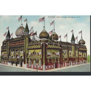 Puede incluir: Postal antigua del Mitchell Corn Palace en Mitchell, Dakota del Sur. El edificio está decorado con maíz colorido y otros granos, coronado por cúpulas de cebolla y banderas americanas. El texto "MITCHELL CORN PALACE, MITCHELL, S. D." es visible.