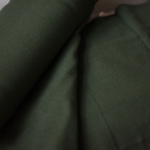 May include: A close-up of a dark green fabric, folded in half. The fabric is soft and smooth, with a subtle texture.