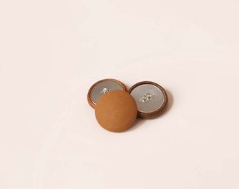 May include: Three round buttons, one brown, one dark brown, and one silver. The brown button is in the center and the other two are on either side.