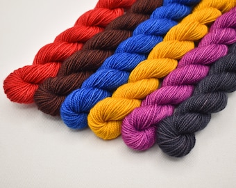 May include: A collection of colorful yarn skeins in shades of red, brown, blue, yellow, magenta, and black. The yarn is arranged diagonally, showcasing the variety of colors and textures. Ideal for knitting and crochet projects.