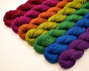 May include: A collection of colorful yarn skeins arranged in a rainbow pattern. The yarn colors include red, pink, orange, yellow, green, blue, and purple. The yarn is tightly wound and appears soft, ideal for knitting or crochet projects.