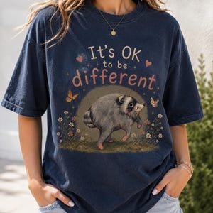 ジモシー・ラクーン「人と違っていても大丈夫」Tシャツ、バイラルミームのラクーンTシャツ、かわいいアライグマTシャツ、面白い動物グラフィックTシャツ