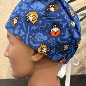 May include: Blue surgical scrub hat with a white tie. The hat has a repeating pattern of Harry Potter characters, including Harry, Ron, Hermione, and Dumbledore.
