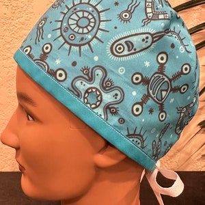 May include: A turquoise blue surgical scrub hat with a white tie. The hat has a pattern of stylized black and white microbes and other shapes.