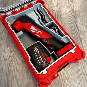 Könnte beinhalten: Ein rotes und schwarzes Milwaukee FUEL Multi-Tool-Kit in einem roten Hartschalenkoffer. Das Kit enthält das Multi-Tool, einen Akku und mehrere Aufsätze. Der Koffer ist geöffnet und zeigt die Werkzeuge und das Zubehör.