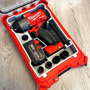 Puede incluir: Un juego de llave de impacto Milwaukee FUEL rojo en un estuche rojo. El juego incluye la llave de impacto, una batería y varios vasos. El estuche está abierto, revelando las herramientas cuidadosamente organizadas. El logotipo de Milwaukee es visible.