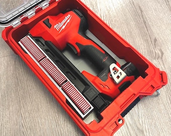 Könnte beinhalten: Ein rotes Milwaukee Elektrowerkzeug-Set in einem roten Hartschalenkoffer. Der Koffer ist geöffnet und zeigt das Werkzeug und Zubehör. Das Werkzeug ist rot und schwarz, mit dem Milwaukee-Logo. Das Zubehör umfasst eine schwarz-weiße Komponente.