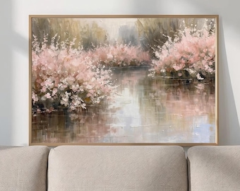 May include: A framed landscape painting depicts a serene river scene. Pink flowering bushes line the banks, reflecting in the water. The artwork has a soft, impressionistic style with muted colors and a natural wood frame.