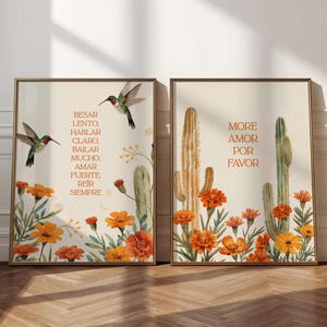 May include: Two framed art prints with botanical illustrations. One features hummingbirds, text, and orange flowers. The other has cacti and the words "MORE AMOR POR FAVOR" in orange. The frames are brown.