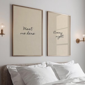 May include: Two framed wall art pieces with the phrases "Meet me here" and "Every night" in black script. The frames are gold-toned, and the background is a light beige. The art hangs above a bed with white bedding.
