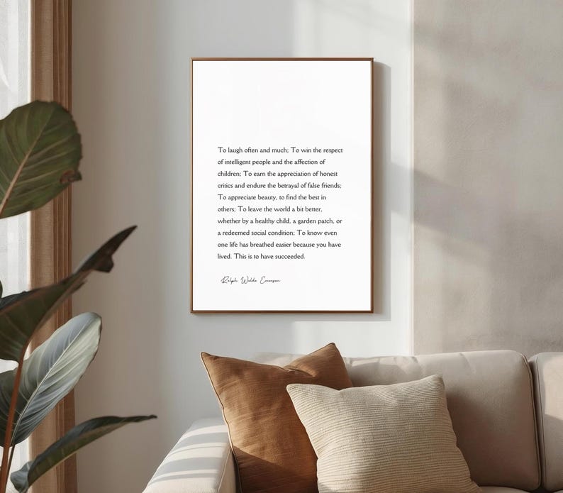 Puede incluir: Una impresi&oacute;n enmarcada con un marco de madera marr&oacute;n cuelga de una pared blanca. La impresi&oacute;n presenta texto negro sobre un fondo blanco, una cita de Ralph Waldo Emerson. La impresi&oacute;n est&aacute; encima de un sof&aacute; beige con cojines marrones y beiges.