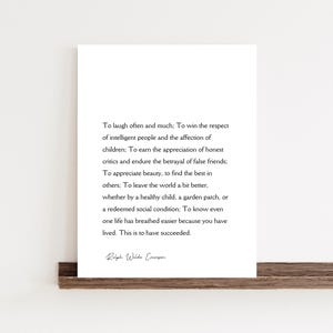 Puede incluir: Impresi&oacute;n enmarcada con texto negro sobre fondo blanco. El texto es una cita de Ralph Waldo Emerson sobre el &eacute;xito. La impresi&oacute;n se muestra en una estanter&iacute;a de madera.