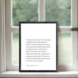 Puede incluir: Una impresi&oacute;n enmarcada con borde negro, con una cita de Ralph Waldo Emerson. El texto es negro sobre fondo blanco, exhibido frente a una ventana.