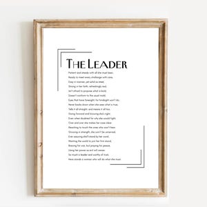 May include: A framed print with the title "THE LEADER" in bold black font. The print features a poem about leadership in a minimalist design, with a light brown wooden frame. The text is centered on a white background.
