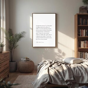 Puede incluir: Un marco dorado cuelga de una pared blanca en un dormitorio. La impresi&oacute;n presenta texto negro sobre un fondo blanco. Tambi&eacute;n se ven una c&oacute;moda de madera, una planta en maceta y una estanter&iacute;a llena de libros.