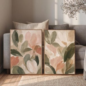 May include: Two rectangular framed wall art prints featuring abstract floral compositions. The paintings display soft brushstrokes in muted shades of sage green, dusty pink, cream, and beige, depicting layered petals and foliage in a botanical arrangement.