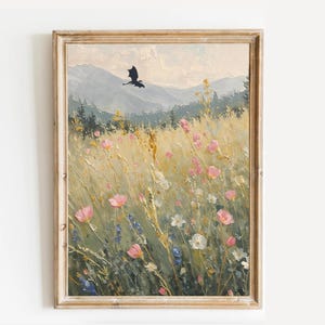 Könnte beinhalten: Ein gerahmtes Ölgemälde auf Leinwand, das ein Feld mit Wildblumen in Rosa-, Weiß- und Gelbtönen unter einem hellen Himmel zeigt. Eine dunkle Silhouette eines fliegenden Drachen ist vor den fernen grauen Bergen und dem Nadelwald zu sehen.