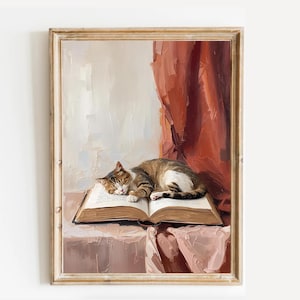 May include: A framed painting depicts a tabby cat asleep on an open book. The artwork features a warm color palette with a red curtain in the background. The painting is in a gold-colored frame.