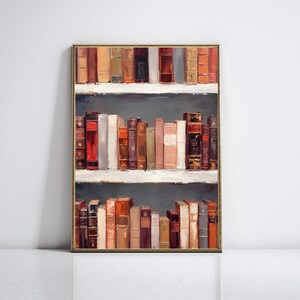 K&ouml;nnte beinhalten: Gerahmtes Kunstwerk mit einem B&uuml;cherregal voller alter B&uuml;cher. Die B&uuml;cher in verschiedenen Farben wie Rot, Braun und Creme sind auf drei wei&szlig;en Regalen vor einem dunkelgrauen Hintergrund angeordnet. Der Rahmen ist goldfarben.