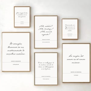 May include: A collection of framed art prints with quotes in Spanish. The prints have a white background with black text and are in gold frames. The quotes include phrases like "El corazón humano es un instrumento de muchas cuerdas."