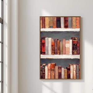 K&ouml;nnte beinhalten: Ein gerahmtes Kunstwerk, das ein B&uuml;cherregal mit alten B&uuml;chern zeigt. Die B&uuml;cher sind in verschiedenen Farben gehalten, darunter Rot, Braun und Beige. Das Kunstwerk hat einen dunkelgrauen Hintergrund und wei&szlig;e Regale.