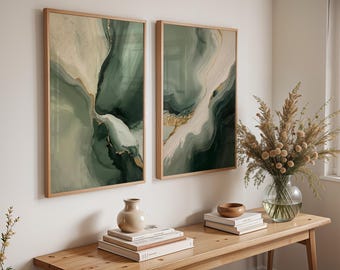 May include: Two framed abstract art prints with a flowing design in shades of green, white, and gold. The artwork is displayed on a white wall above a wooden table with decorative items, including a vase and books.