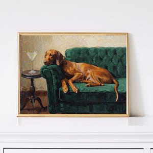 May include: A framed painting shows a brown dog resting on a buttoned, emerald green velvet sofa. A martini with olives is on a small side table. The artwork is in a gold frame, with a vintage style.